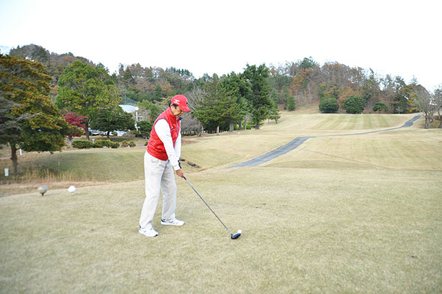 赤ベストを着てゴルフをする男性。今どきの６０歳はアクティブです。